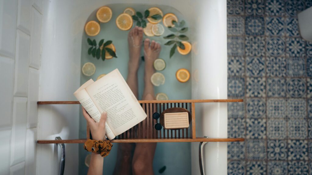 A tranquil bathtub with citrus fruits, book, and self-care essentials for relaxation.
